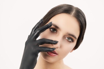 Fototapeta na wymiar Light-skinned girl with a black hand from the paint. Looking straight into the camera is covered by the hand.