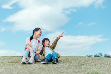 芝生に座る小学生（指差す）
