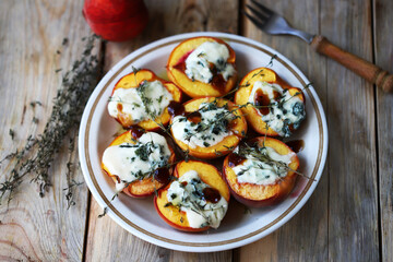 Peaches halves with blue cheese and thyme on a plate.