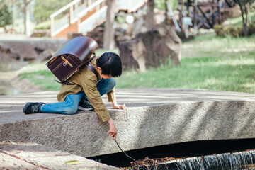 学校帰りに川で遊ぶ小学生の男の子
