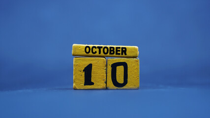 Wooden block calendar showing October 10. Isolated on blue background