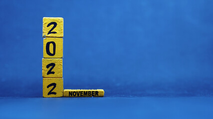 Wooden block calendar showing November 2022. Isolated on blue background