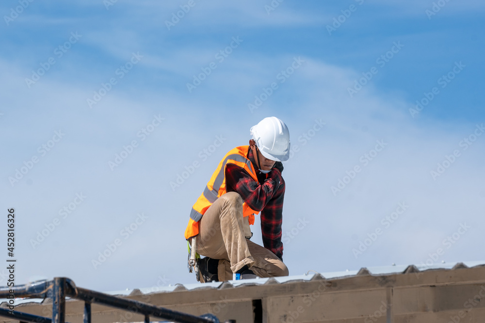 Poster roofer worker in protective uniform wear and gloves working installing metal sheet on top of the new