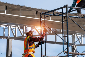 Construction worker wearing safety harness and safety line with tools are climbing scaffolding working at height.