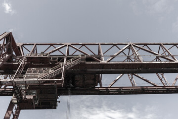 Fototapeta na wymiar Industrial architecture overhead structure against a grey sky, horizontal aspect