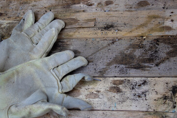 Old worn leather construction work gloves on wooden background