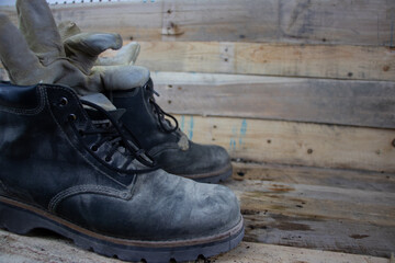 Old worn leather construction work boots on wooden background