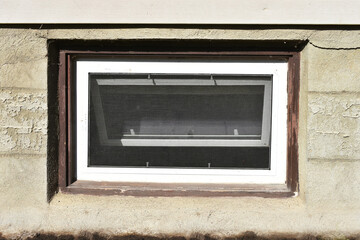 An image of an old basement window with brown painted trim.
