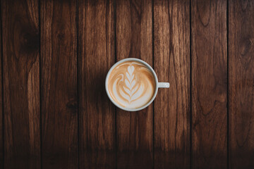 Latte art coffee on wooden table in coffee shop