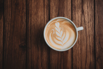 Latte art coffee on wooden table in coffee shop