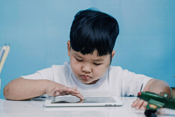 Asian little boy touching and watching on tablet computer at home, Close up.