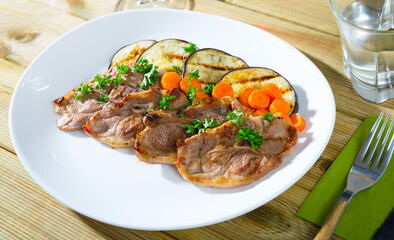 Tasty mutton loin chops grilled with eggplant slices and carrots garnished with fresh parsley