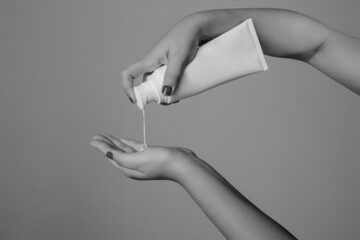Manos femeninas aplican crema hidratante para el cuidado cosmético de la piel aislado en el fondo...