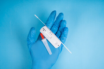 Doctor in blue gloves holding covid-19 test kit, rapid test for COVID-19