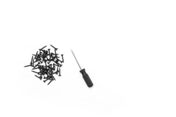 Black self-tapping screws and a screwdriver on a white background. Close-up