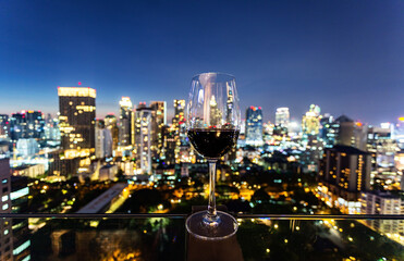 Plakat Wine glass with red wine in city bokeh background.Celebrate Success