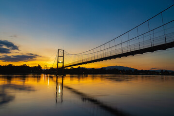 Fototapeta na wymiar Night suspension bridge suspension bridge with river reflection at twilight