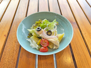Potato salad in ceramic bowl on wooden table, selective focus