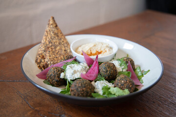 Closeup of healthy organic vegan salad with falafel and crispy bread. Healthy Asian vegan lunch served in rustic cafe. Organic and clean food. Healthy and balanced diet eating