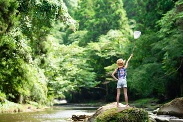 渓流で虫取り網を持つ子供