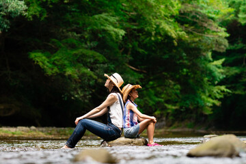 渓流で一緒に座っておしゃべりをする母と娘