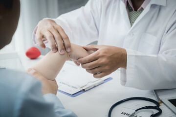 Orthopaedic doctor doing physical examination patient with wrist pain at the clinic. Physical...