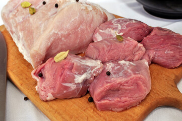 Raw meat with cardamon and pepper on the carving board, prepared for barbecue, close up. Portion of fresh pork chops