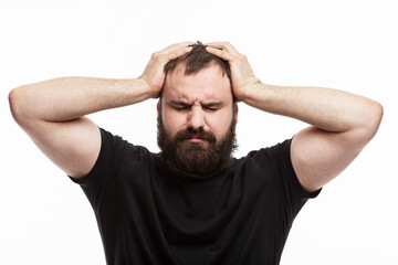 A man with a beard is emotionally holding his head. Depression and stress. White background. Brunette in a black T-shirt.
