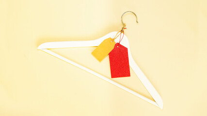 White wooden clothes hanger with tags. Red price tag.