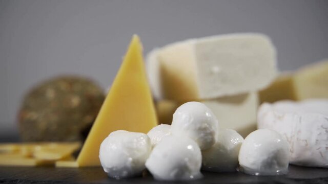 Various types of cheese lie on the table. Gourmet food. Delicious delicacy. Dairy products. Close-up, the camera rotates.