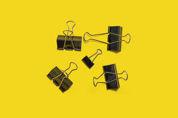 five black paper clip on a yellow background