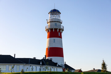 Lighthouse in red and white colors on the seashore, river bank or lake shore. Lighthouse hotel in a fishing village. Travel and tourism concept. Russia, Ryazan region, near the village Shumash.