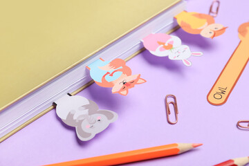 Cute bookmarks with book and stationery on color background
