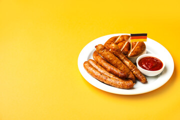 Plate with tasty sausages, sauce and flag of Germany on color background