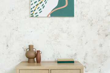 Vases with books on shelf near light wall