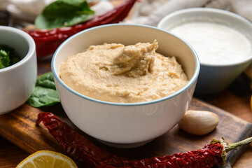 Bowl with tasty hummus and ingredients on table, closeup