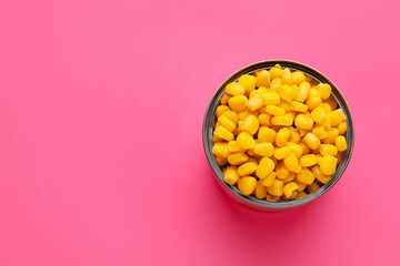 Opened tin can of corn kernels on color background