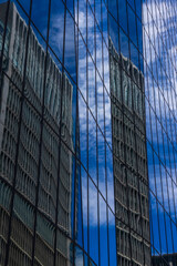 Fototapeta na wymiar 高層ビルのガラス窓に反射する隣のビルと雲