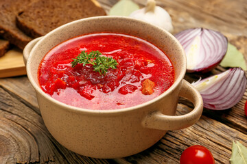 Pot with tasty borscht on wooden background