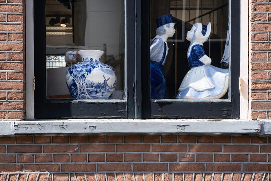 DELFT, THE NETHERLANDS - JULY 29 2021: Delft blue vase and couple in love are standing in front of the window of a shop in Delft