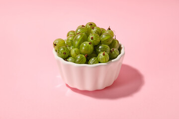 Bowl with fresh ripe gooseberry on color background