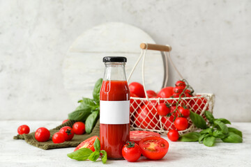 Bottle of tasty tomato juice on light background
