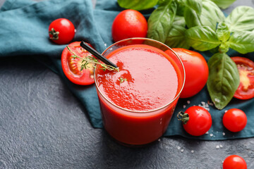 Glass of tasty tomato juice on dark background