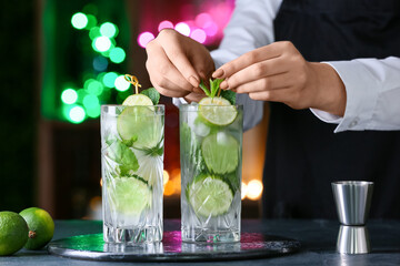 Female bartender making fresh mojito on table in bar