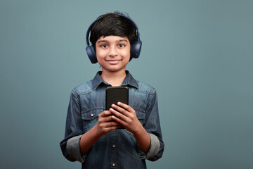 Smiling boy wearing a headset holding a smart phone in hand