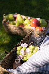 fruit picnic basket in grass summer apples pears grapes flowers tomatoes glasses drinks striped blanket