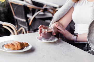 Young woman sitting in a cafe in the morning and enjoying hot chocolate and croissant