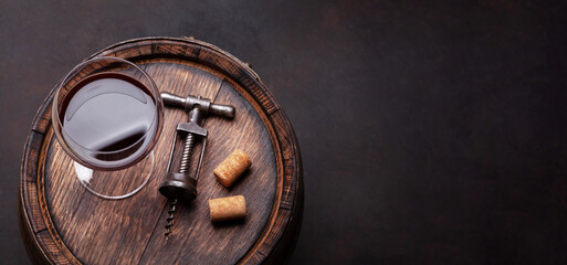 Red wine glass and vintage corkscrew on old barrel