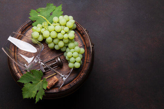 Wine glass and white grape on old barrel
