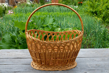 Fototapeta na wymiar A large wicker basket on a gray table against a background of green grass.Picnic Basket